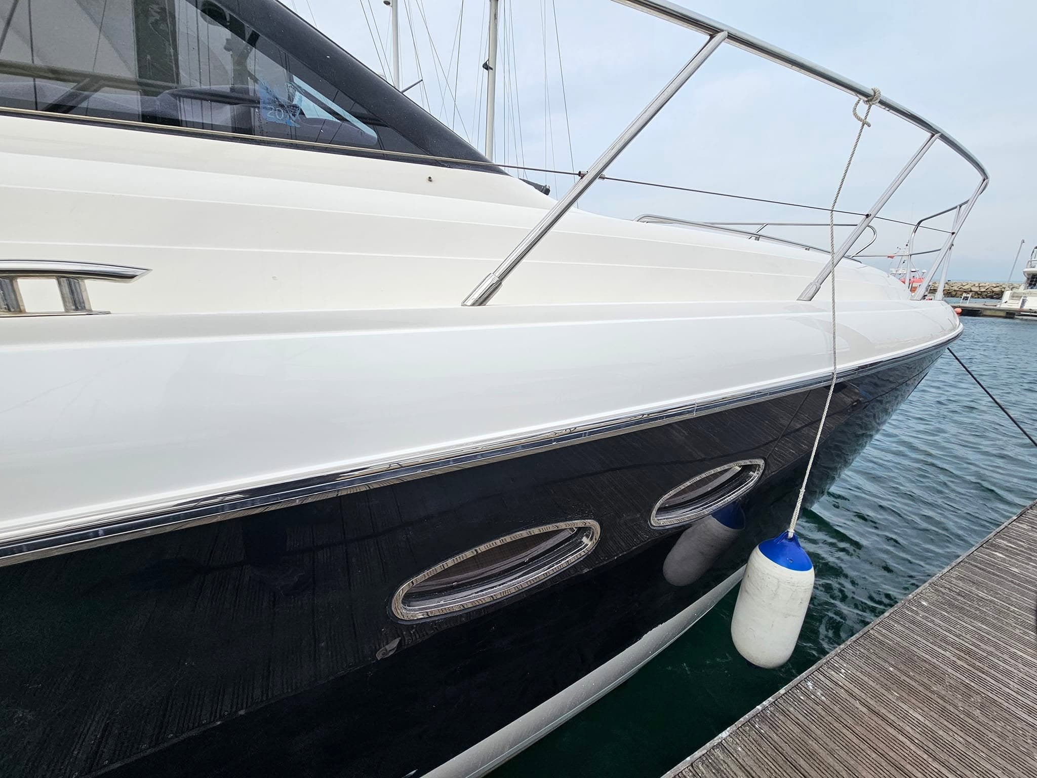 Freshly polished glossy white motor yacht hull at Portland Marina, finished by Ember Marine